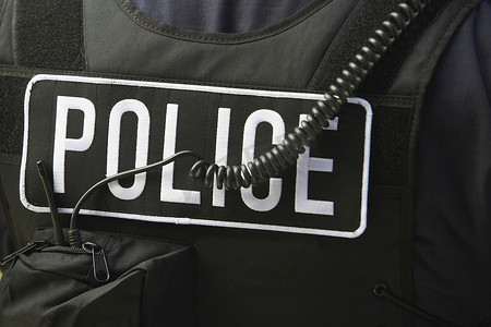 防护夹克上警察标志和绳索的特写后视图