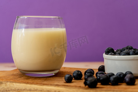 在现代、简约的环境中，一杯牛奶和一些蓝莓旁边的正常视图。