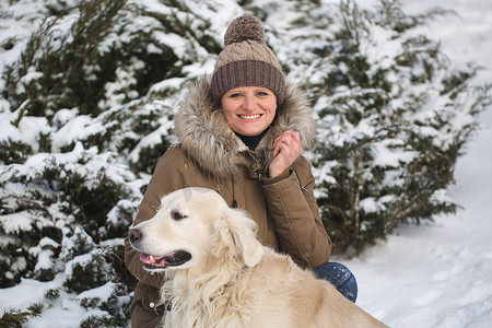 美丽的女孩和她的狗在雪地里玩耍。