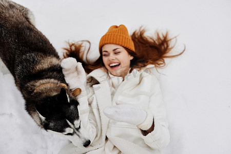 雪地里的年轻女子和狗玩耍有趣的友谊寒假