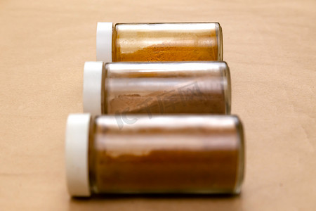 棕色背景上的三罐调味料，有选择的焦点。