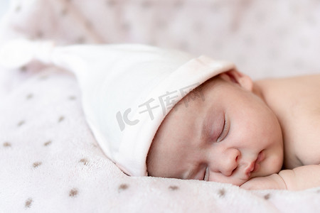 休息小憩摄影照片_童年、护理、母性、健康、医学、儿科概念 — 特写小和平平静的赤裸婴儿新生女婴戴着粉色帽子睡觉休息，躺在柔软的床上小憩。