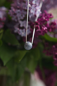 天然石材制成的项链，配有银色配件，白色鸵鸟羽毛上饰有紫色紫丁香花。
