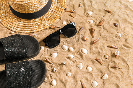 夏季沙滩装、人字拖、帽子、太阳镜和沙滩上的贝壳。