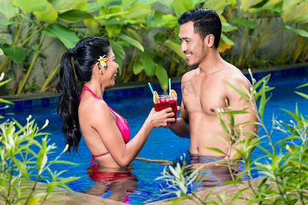在亚洲的游泳池里喝酒的夫妇