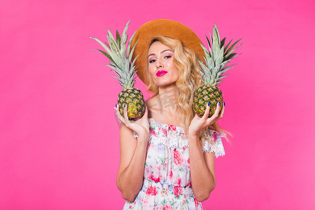 幸福的女人和菠萝在粉红色背景与 copyspace 的画像。