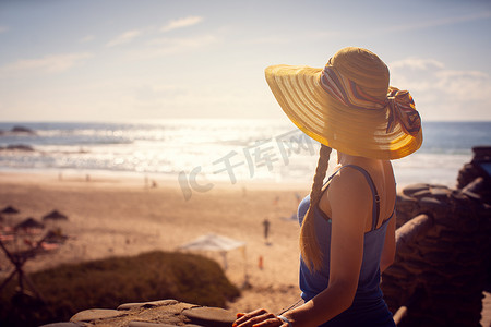 连衣裙帽子摄影照片_看海的女人坐在靠近海滩的地方