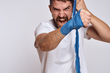提高技能摄影照片_一个身穿白色 T 恤拳击绷带的运动型男子，手上缠着拳击练习，提高技能