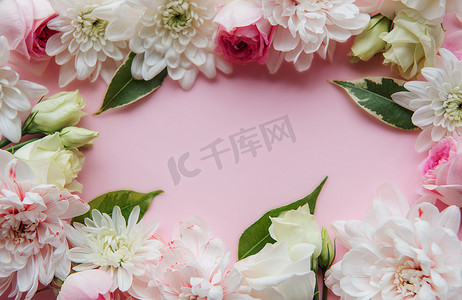 白色的花朵摄影照片_框架由柔和的粉红色背景上的花朵制成。