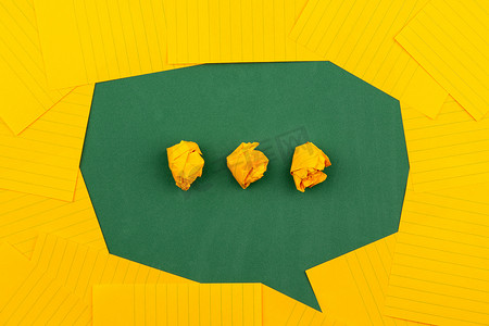 橙色对话框摄影照片_橙色的纸片放在绿色的学校董事会上，用三张皱巴巴的纸形成一个聊天泡泡