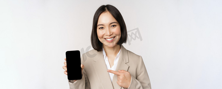 手机界面摄影照片_显示智能手机应用程序界面、手机屏幕、站在白色背景上的亚洲企业女性肖像