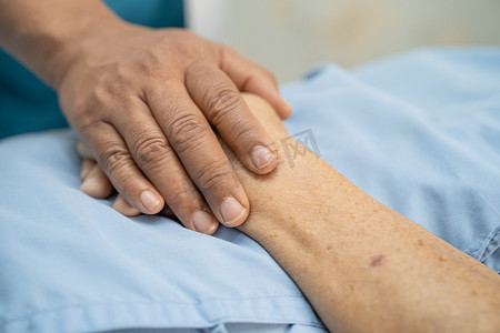 医生手牵着亚洲老年或老年老妇人的手，在护理医院病房里充满爱、关怀、帮助、鼓励和同情，健康强大的医疗理念