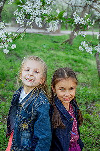 两个女孩在春天的花园里享受落花