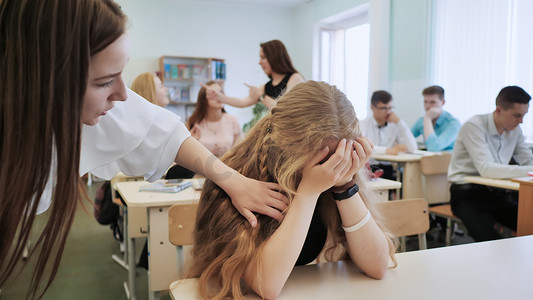 这个女孩是一个在课堂上哭泣的女学生，她的同学安慰她。