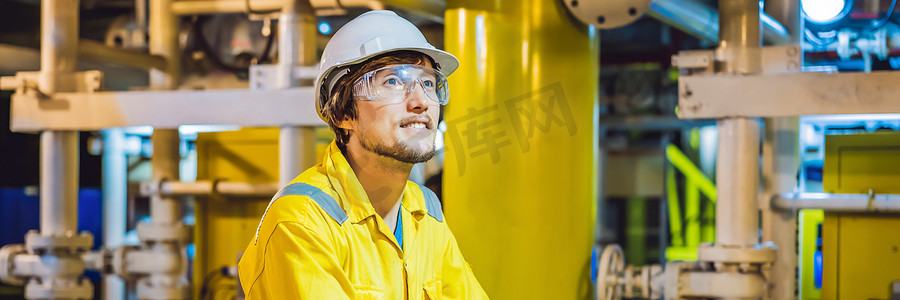 在工业环境、石油平台或液化气厂横幅、长格式中穿着黄色工作服、眼镜和头盔的年轻人
