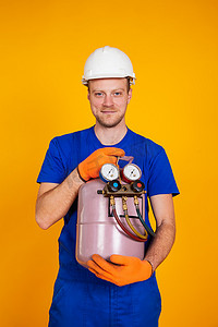 拿收集摄影照片_一名男空调维修工手里拿着一个氟利昂钢瓶，正在给空调开空调。