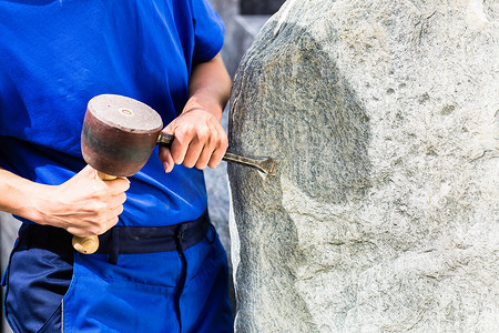 石匠用大锤和铁在巨石上工作