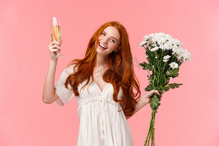 可爱、快乐、漂亮的红头发女人庆祝，参加令人敬畏的 b 日派对以纪念她，手捧白色花束，举杯香槟，欢呼，粉红色背景