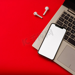 苹果笔记本摄影照片_俄罗斯图拉 — 2019 年 5 月 24 日：红色背景中的苹果 iphone X 和 Airpods，带笔记本。