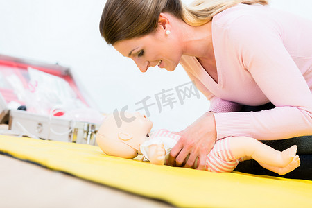 急救措施摄影照片_参加急救课程的妇女在婴儿 d 上练习婴儿的复苏