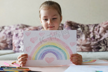 女孩在家里画彩虹，这是英国国家医疗服务体系 (NHS) 的象征。
