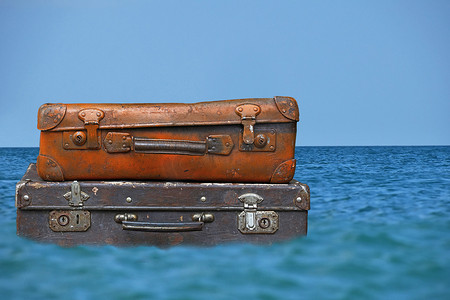 老式旅行箱漂浮在蓝色海水中