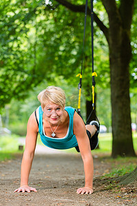 弹力带运动摄影照片_做悬吊吊带教练运动的女人