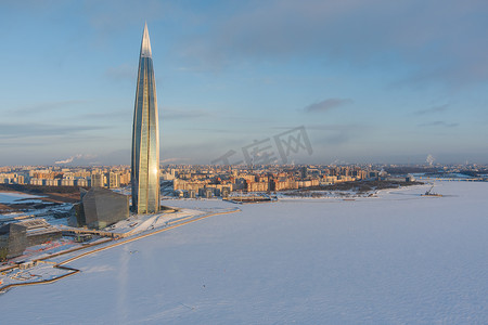 在施工的建筑摄影照片_俄罗斯，圣彼得堡，2022 年 1 月 8 日：Lakhta 中心摩天大楼在日落的冬季寒冷的夜晚，石油公司 Gazprom 办公室未来的主楼，粉红色的建筑