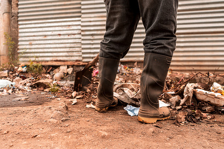 在贫困社区收集垃圾的市政工人的靴子特写
