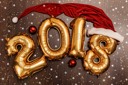 明亮的金属金气球人物2018年、圣诞节、新年气球，深色木桌背景上有闪闪发光的星星