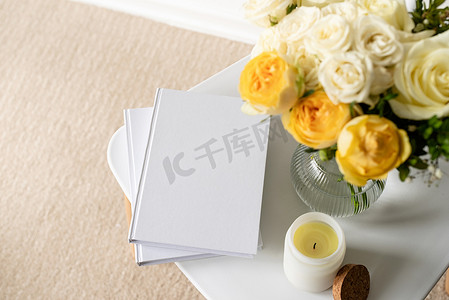 时尚椅子上的白书空白封面模型，配有玫瑰花束、高角度视图