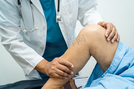 脊椎治疗摄影照片_亚洲医生物理治疗师在骨科诊所护士医院检查、按摩和治疗老年患者的膝盖和腿部。
