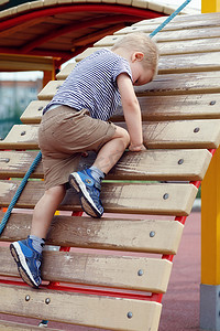 攀岩男孩摄影照片_爬木墙的孩子顽固地爬上去
