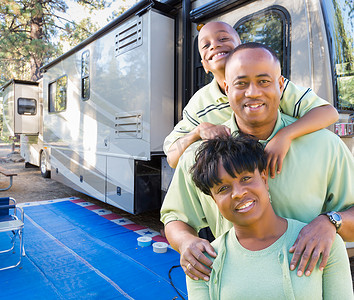 快乐的非洲裔美国家庭在营地美丽的房车前。