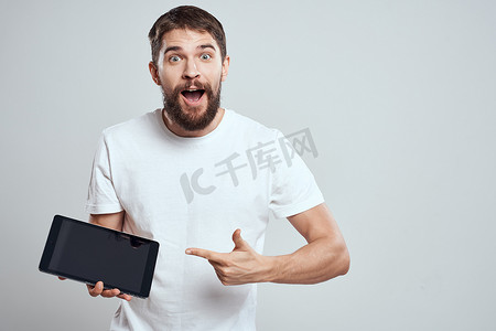 手拿平板电脑的情绪化男人触摸屏新技术浅色背景裁剪视图复制空间