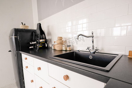 复古风格的黑色水槽，带轻型厨房的水龙头，厨房家具，黑色大理石台面，厨柜，墙上的白色瓷砖
