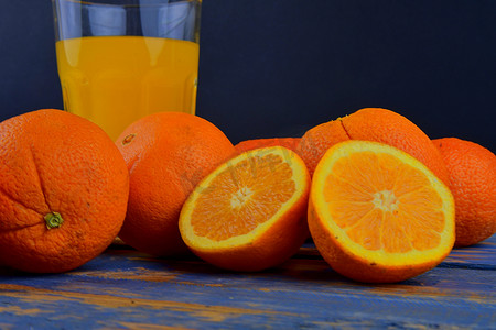 橘子、橙子、一杯橙汁和蓝色木质背景上的手动柑橘挤压机。