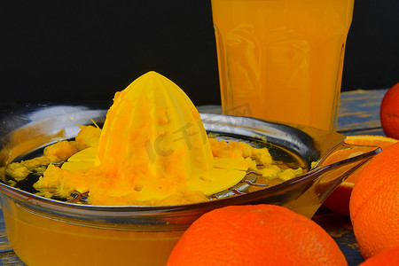 橘子、橙子、一杯橙汁和蓝色木质背景上的手动柑橘挤压机。