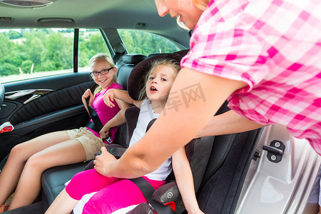 扣好安全带摄影照片_母亲在汽车安全座椅上系好孩子