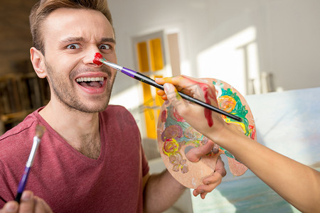 女人用画笔画男友拿着调色板鼻子的裁剪镜头
