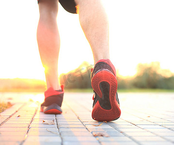 公路奔跑摄影照片_非洲男子在日出或日落时在户外锻炼时双腿奔跑。