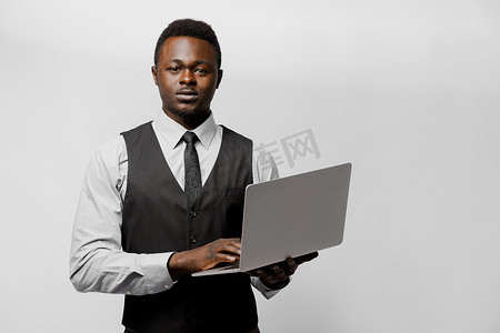 严格的非洲老板穿着商务服装，带着笔记本电脑。