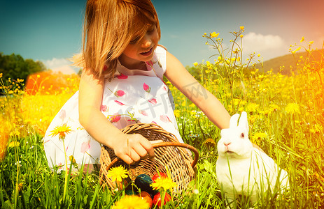 女孩在草地上用鸡蛋抚摸复活节兔子