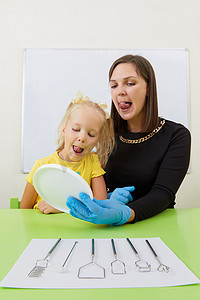 发音训练摄影照片_言语治疗师在办公室训练发音时与小女孩一起工作