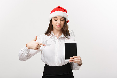 企业概念-圣诞节主题的年轻白种人女商人显示并指向数字平板电脑。