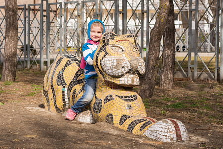 阿纳帕操场上坐在老虎雕塑上的快乐女孩