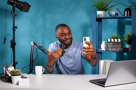 坐在录音室里的非洲裔美国视频博主在智能手机上通过实时视频通话与粉丝互动