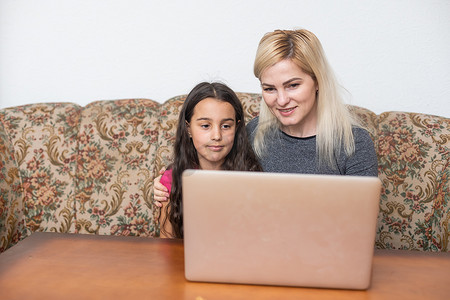 幸福的家庭母女使用笔记本电脑技术观看视频娱乐，客厅享受家庭生活