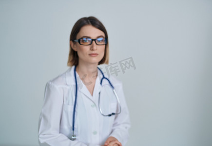 职业摄影照片_职业女医生身穿医用长袍，戴眼镜，脖子上挂着听诊器