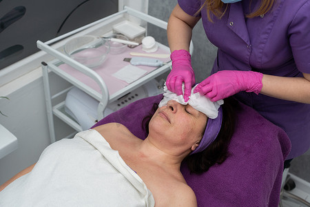 美容师用卫生气体将去角质制剂涂抹在顾客脸上